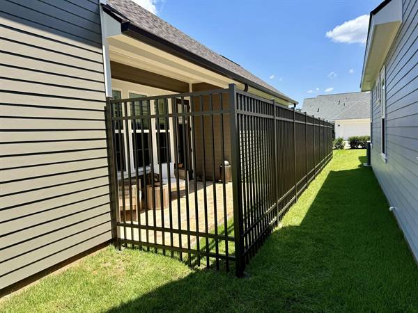 Black aluminum ornamental fence enclosing a patio between two homes