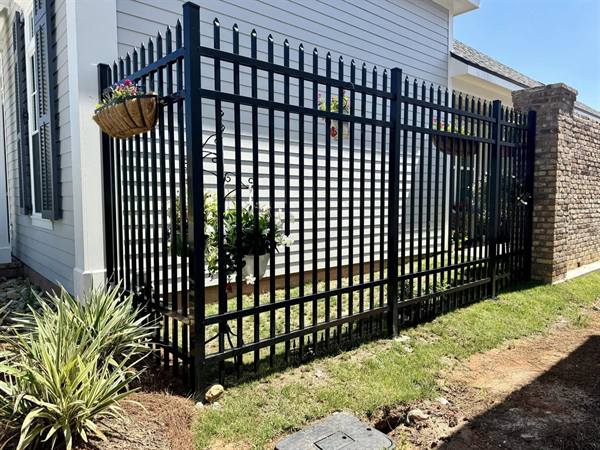Black aluminum fence and gate beside a brick column