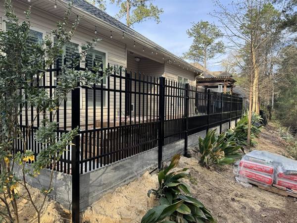 Black aluminum fence atop a retaining wall around a back porch