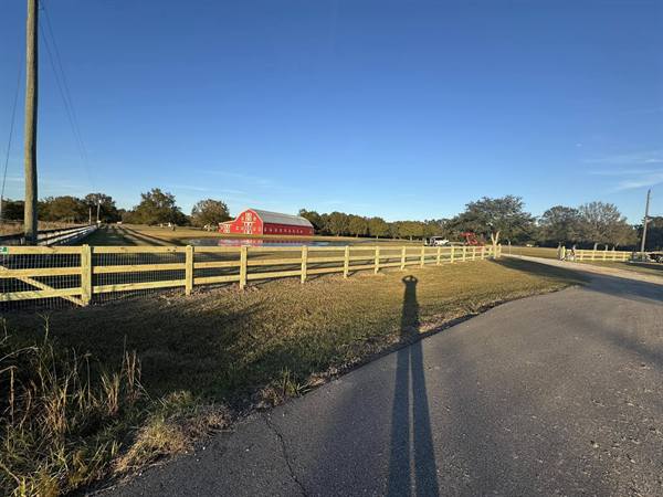 Three-rail pasture fence with welded wire, red barn and pond behind