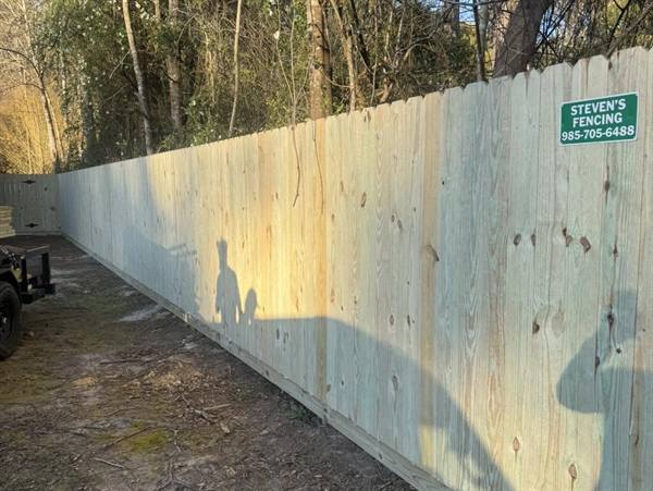 Long treated pine privacy fence with the Steven's Fencing sign