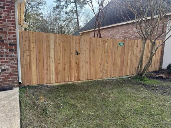 Cedar privacy fence and gate along the side of a brick home