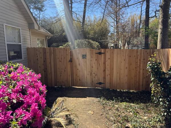 Arched cedar gate framed by blooming azaleas