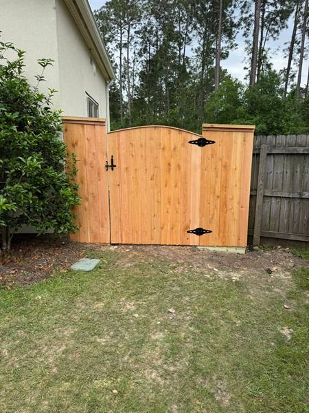 Arched cedar gate and new panels next to an older weathered fence