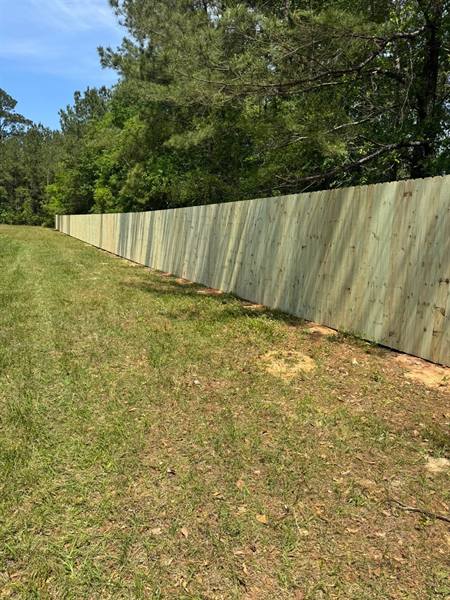 Long treated pine privacy fence line on acreage