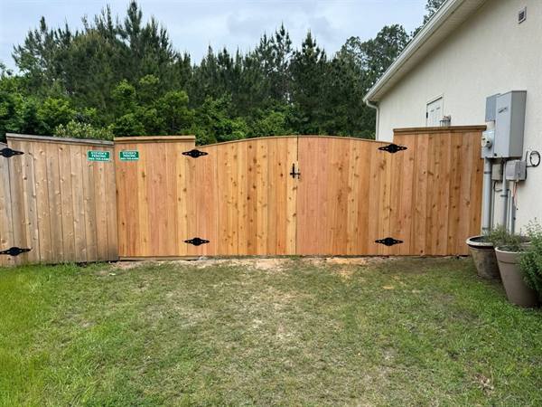 Arched cedar double gate between fence panels