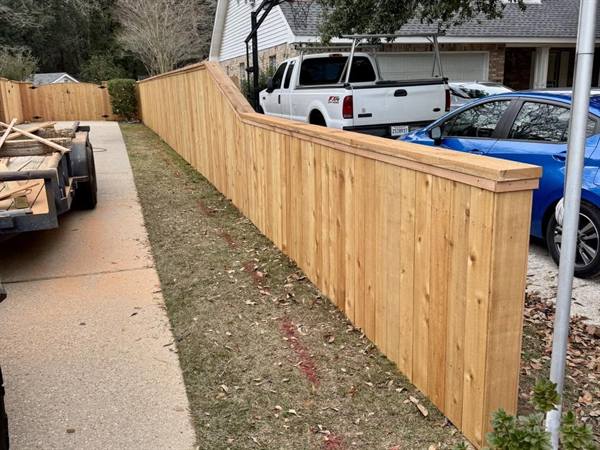 Capped cedar fence stepping down along a driveway