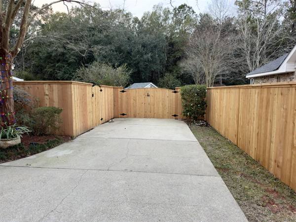 Capped cedar fencing and double gate around a driveway courtyard
