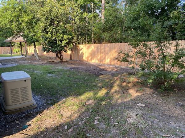 Stained privacy fence across a shaded backyard