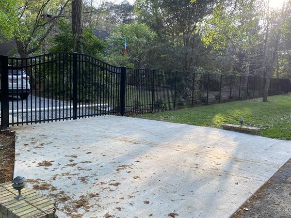 Black aluminum fence with arched gate along a new driveway