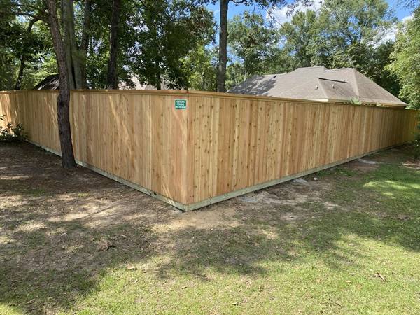 Cedar privacy fence with top cap wrapping a backyard corner