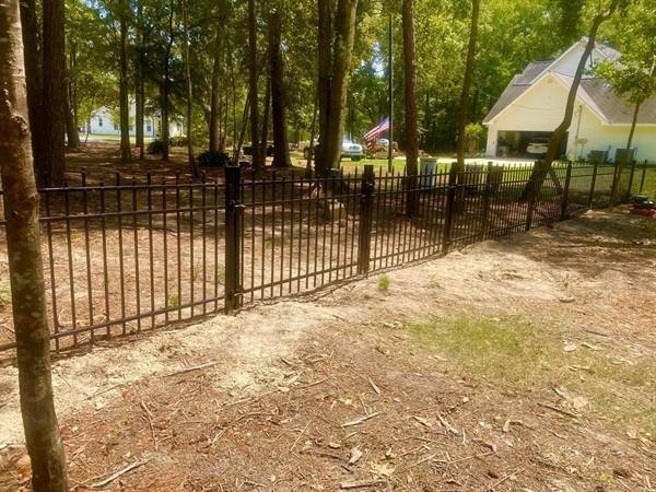 Black aluminum fence winding through a wooded yard