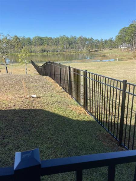 Black aluminum fence stepping down to a pond
