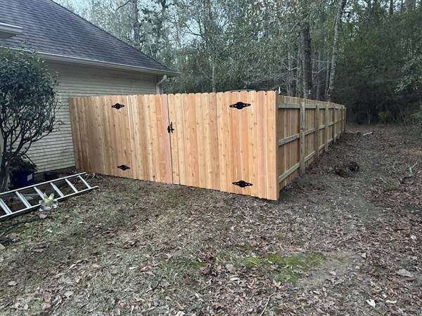 Cedar privacy fence with double gate at a wooded backyard